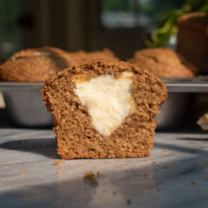 An apple butter cheesecake muffin cut in half to show the soft texture and cheesecake filling.