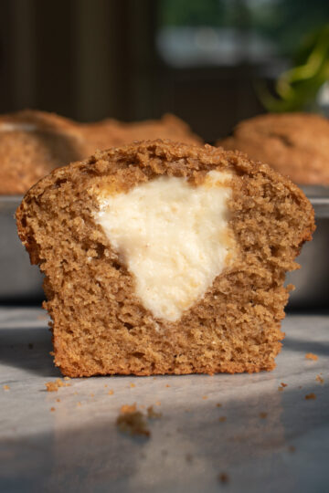 An apple butter cheesecake muffin cut in half to show the soft texture and cheesecake filling.