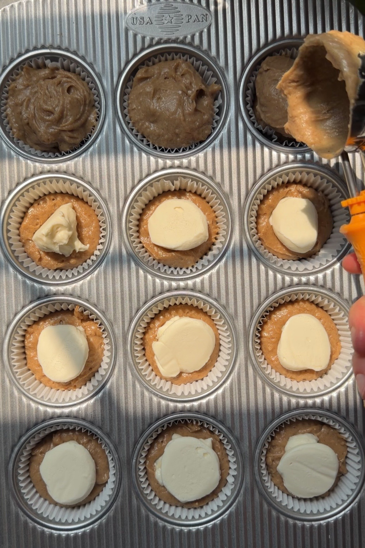 Apple butter cheesecake muffins being portioned into 12 muffin liners before baking.