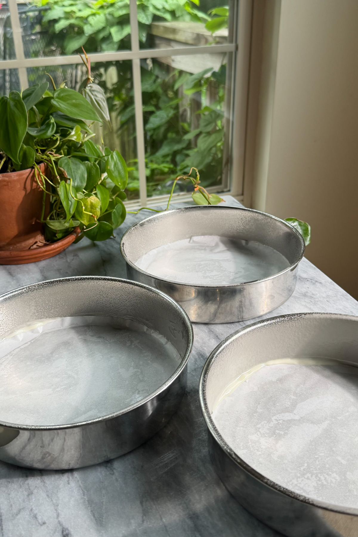 Three 8-inch cake rounds that are lined and greased before adding the chocolate cake batter for Matilda's Chocolate Cake.