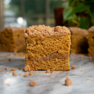 A slice of moist pumpkin coffee cake topped with cinnamon streusel and a layer of streusel in the middle.