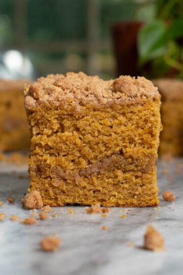 A slice of moist pumpkin coffee cake topped with cinnamon streusel and a layer of streusel in the middle.