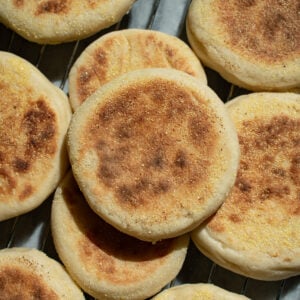 Sourdough discard english muffins piled on each other on a cooling rack.