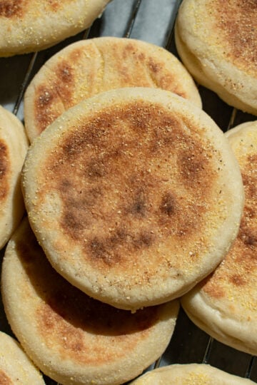 Sourdough discard english muffins piled on each other on a cooling rack.