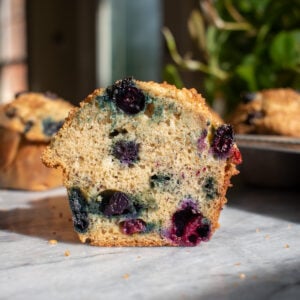 A banana blueberry muffin cut in half on a marble countertop.