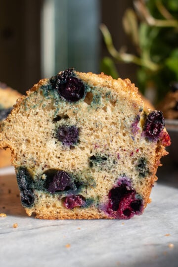 A banana blueberry muffin cut in half on a marble countertop.