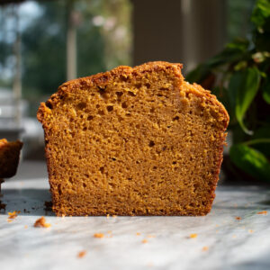 A slice of pumpkin bread in front of a window.