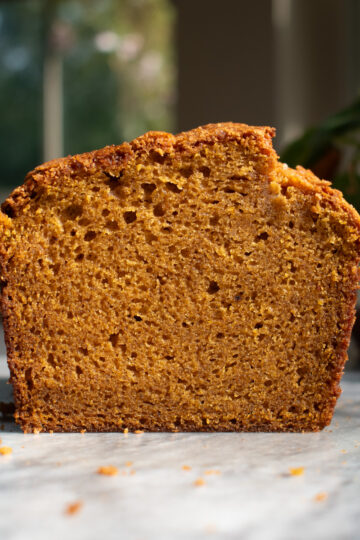 A slice of pumpkin bread in front of a window.