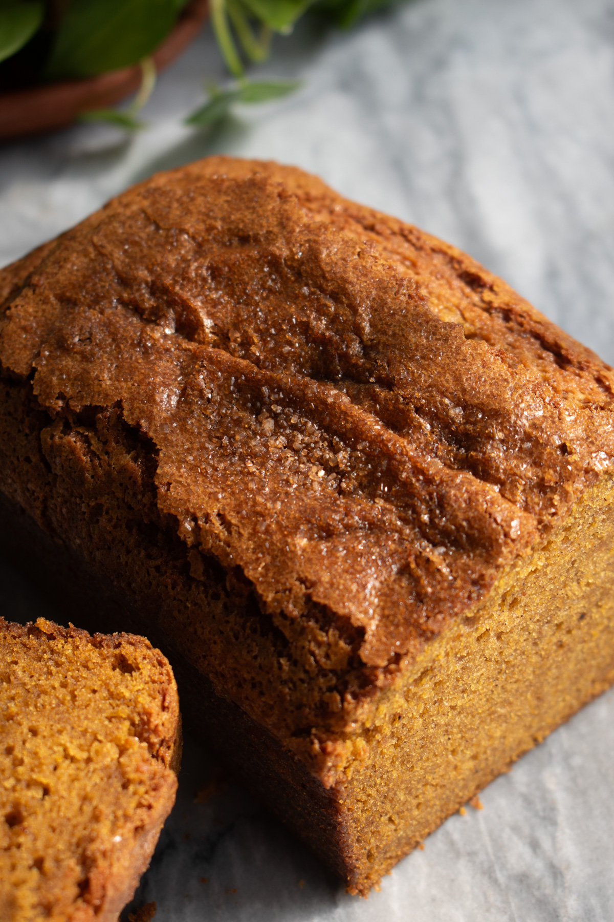 Crackly sugar-topped pumpkin bread on a marble countertop.