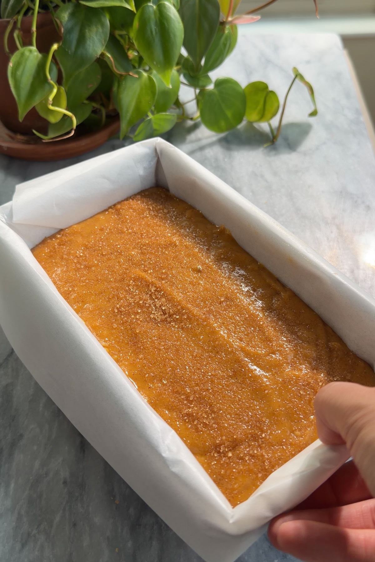 Pumpkin bread batter in a lined 9x5 loaf pan before baking.