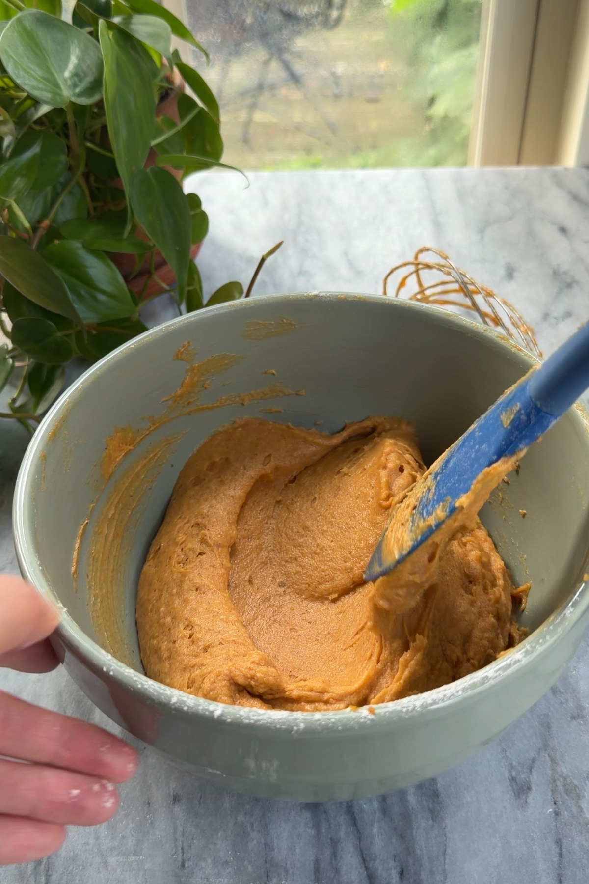Pumpkin cake batter in a green mixing bowl to be added to pumpkin cake cheesecake.