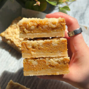 Three pumpkin pie crumb bars stacked on top of each other.
