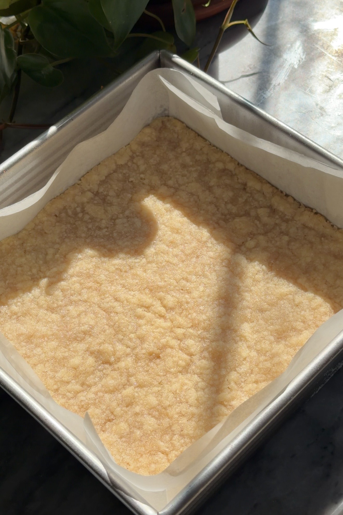 The par-baked shortbread crust for pumpkin pie crumb bars in a lined 8x8 baking pan.