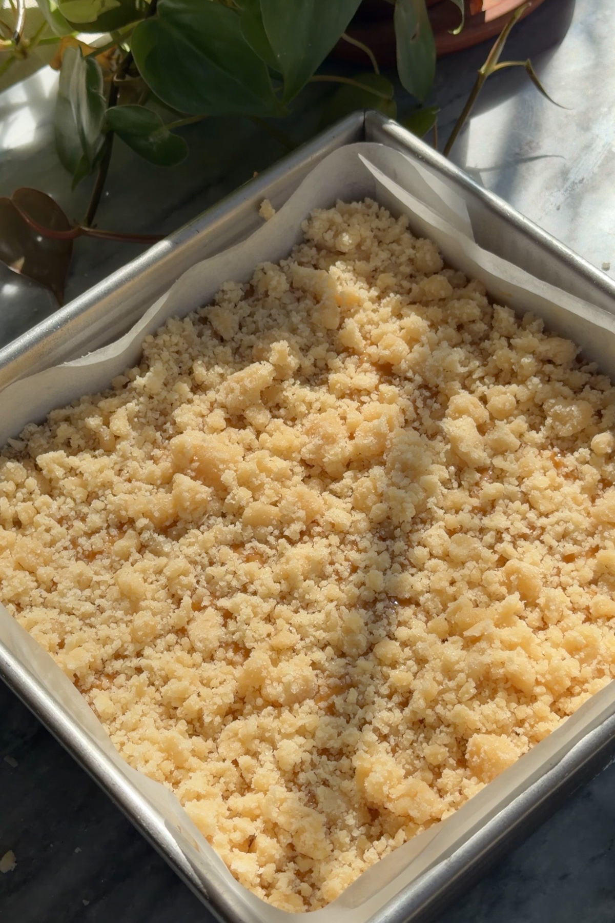 Pumpkin pie crumb bars in a lined 8x8 baking pan before baking.