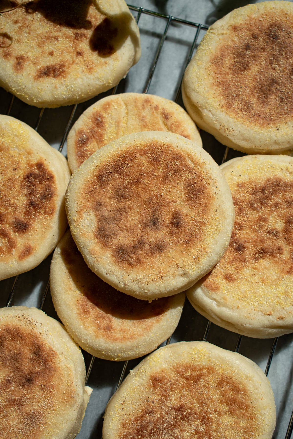 Sourdough discard English muffins lying on top of each other on a metal cooling rack.