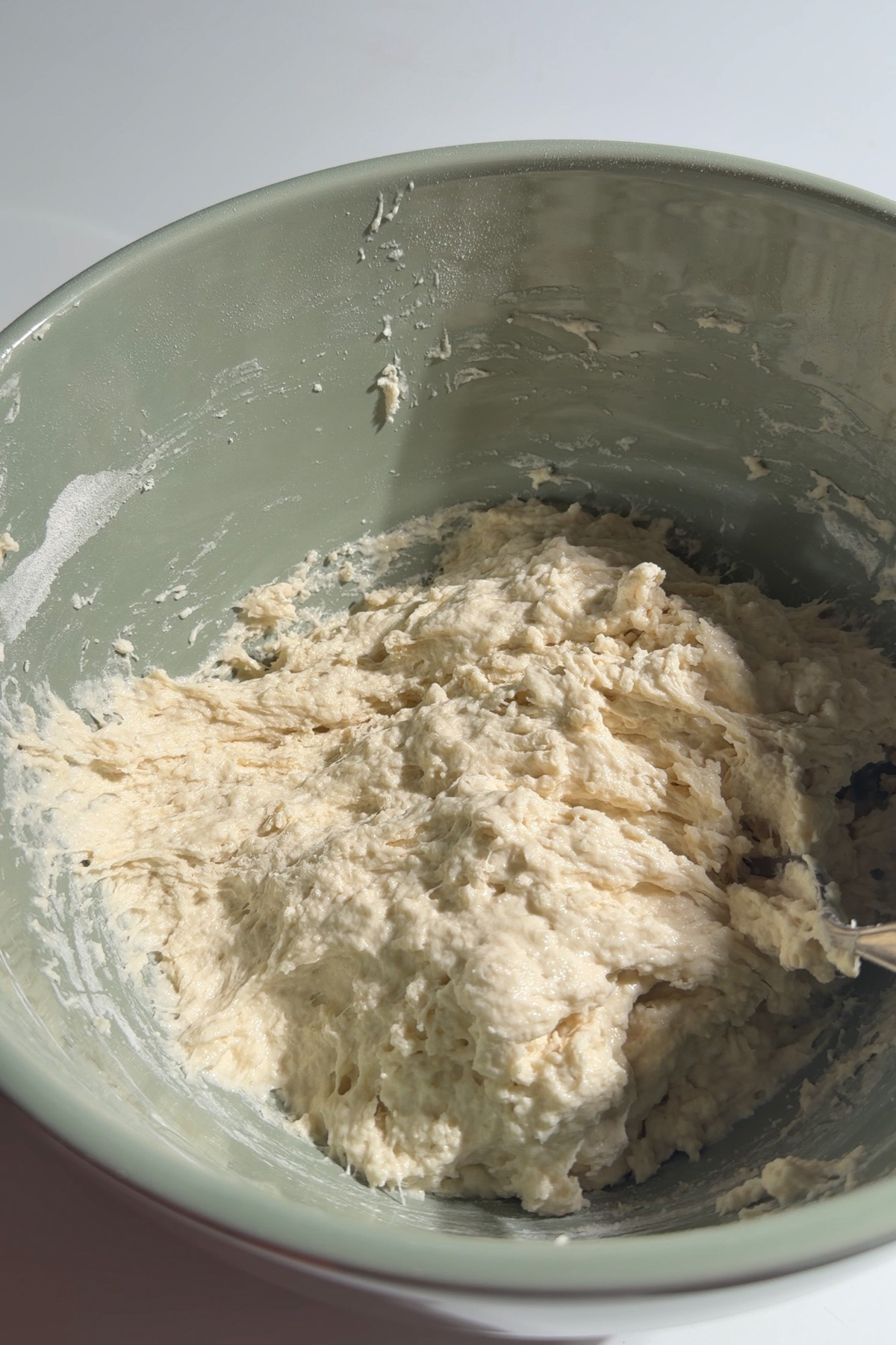 Shaggy sourdough discard focaccia bread dough in a green mixing bowl before doing the stretch and folds.