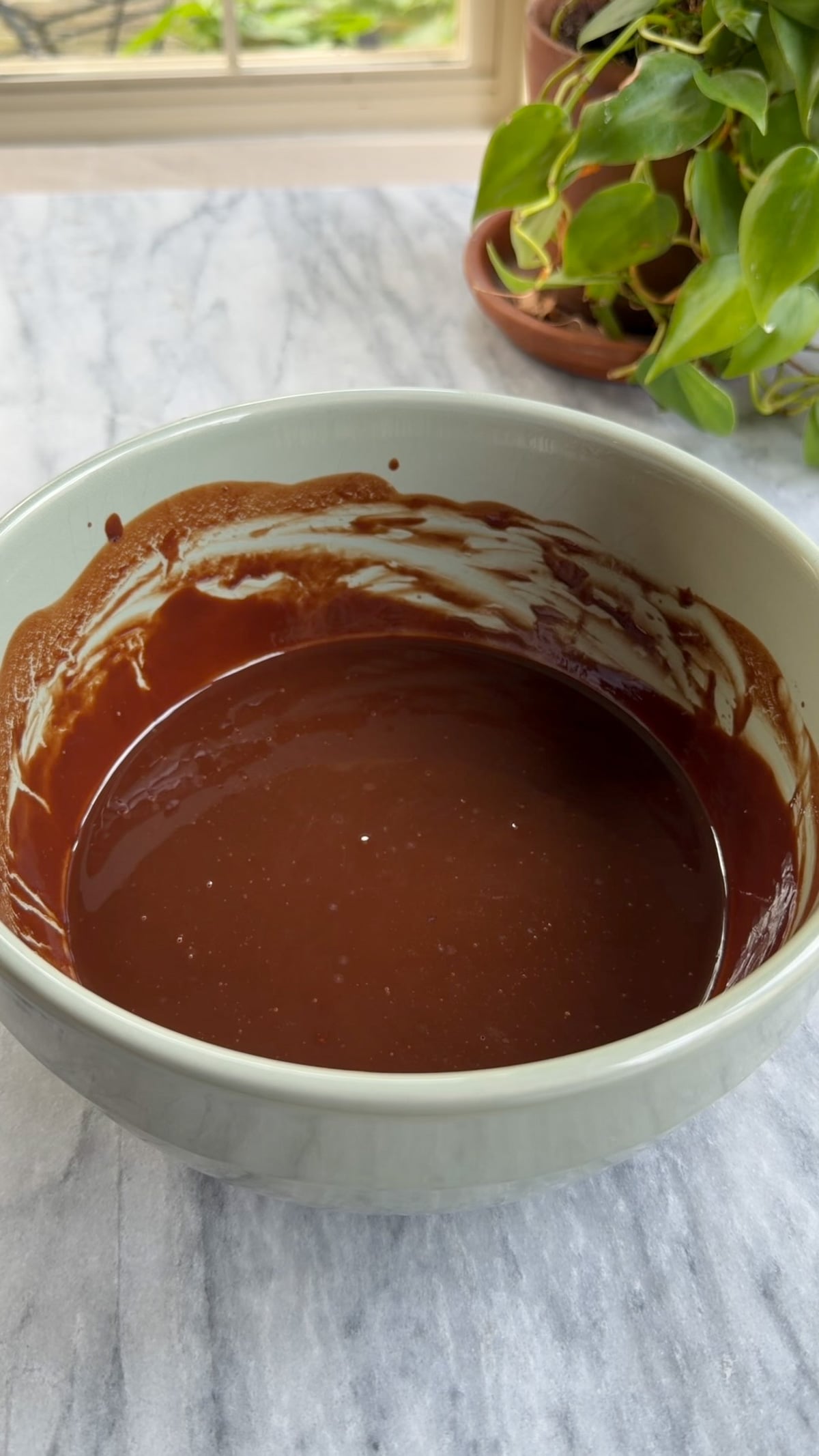 Melted butter and chocolate in a green mixing bow for brownies.