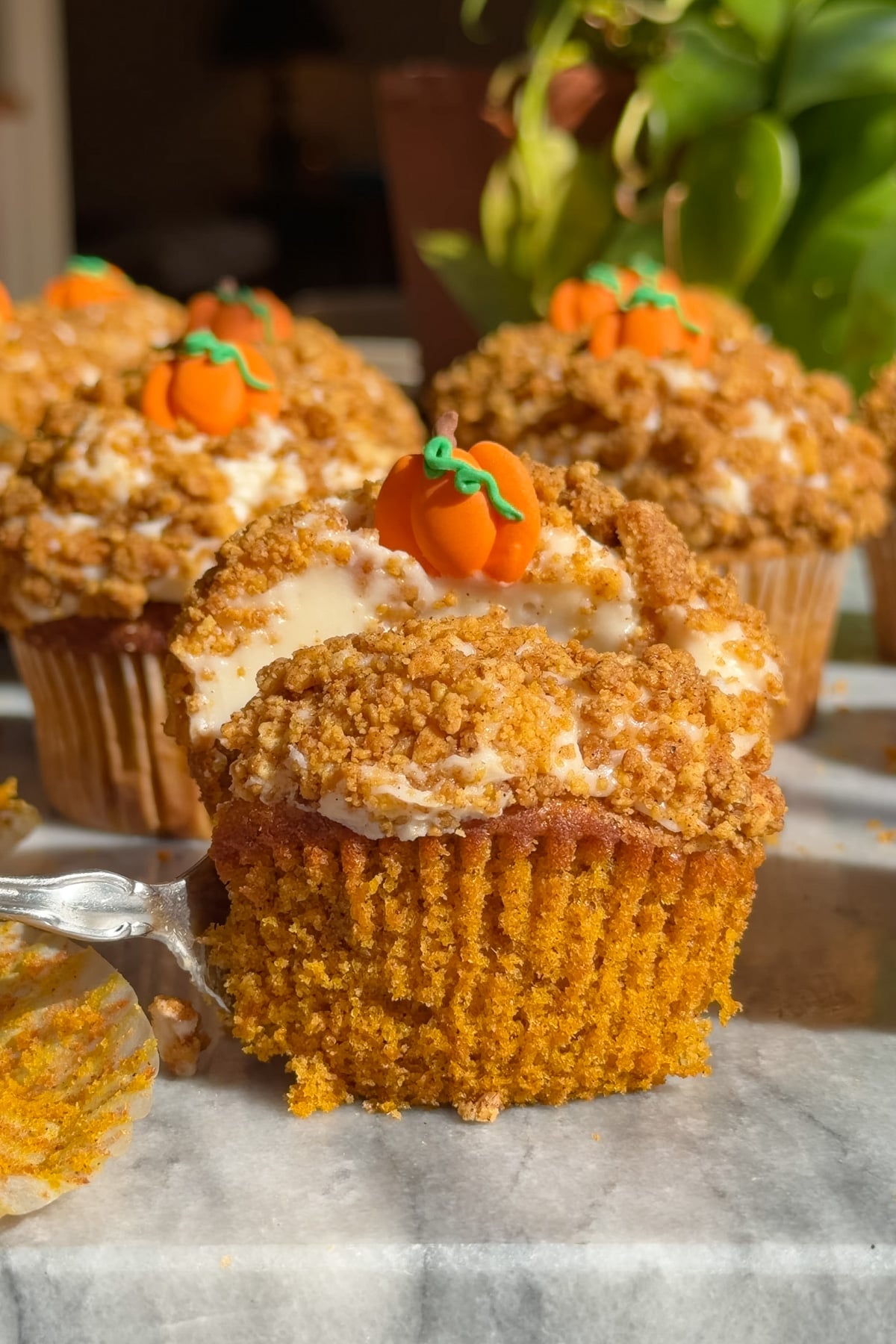 Pumpkin crunch cupcakes coated in Golden Oreo crumble and topped with pumpkin decorations.