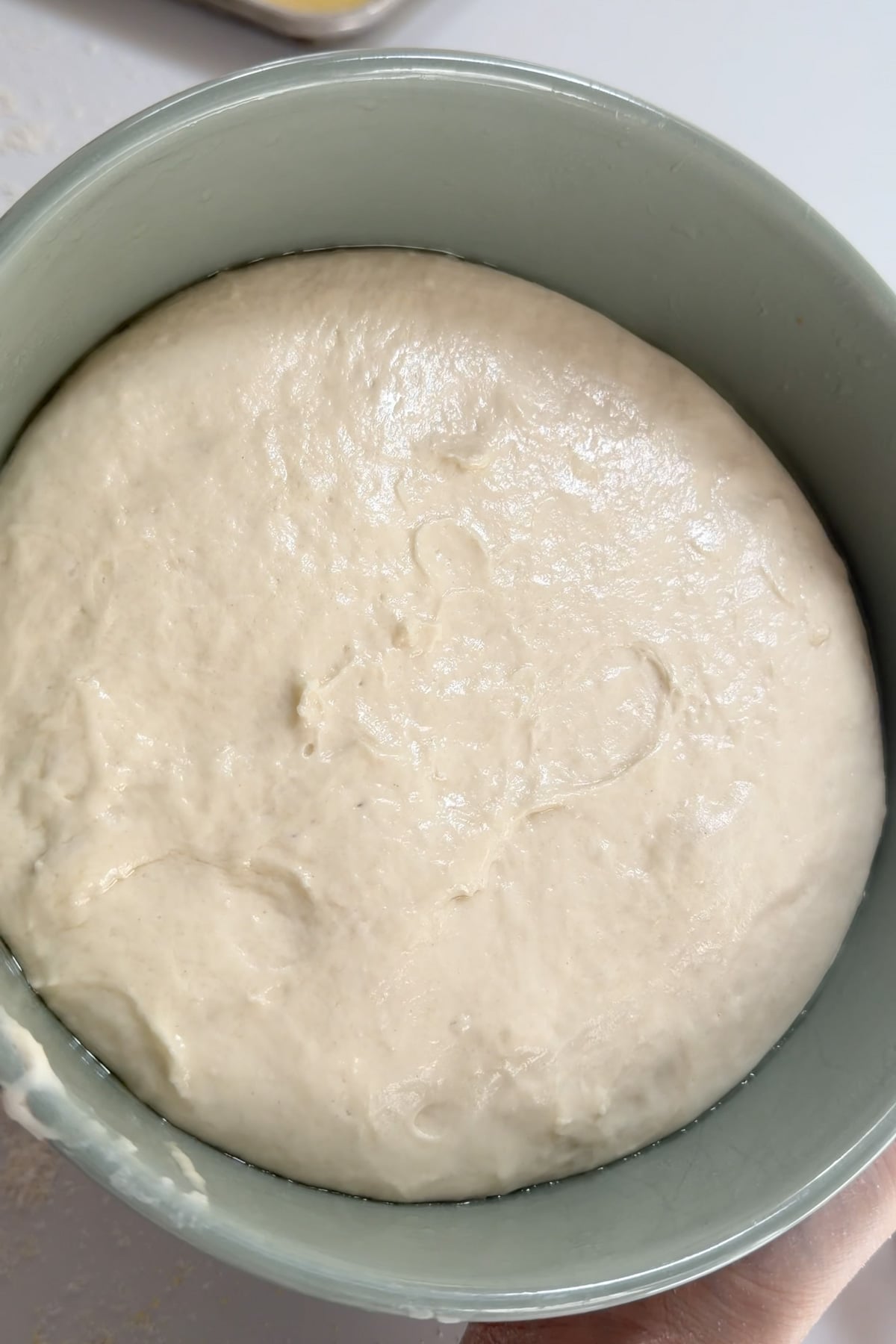 The dough for sourdough discard English muffins in a green mixing bowl after the first rise.